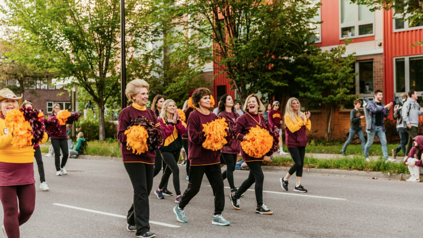 Alumni walking with pom-poms in the Homecoming parade